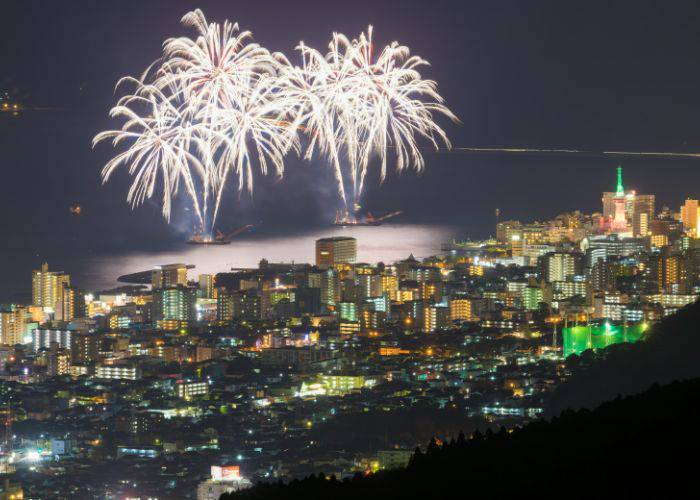 Two boats setting off fireworks on Beppu Bay, lighting up the sky above Beppu.